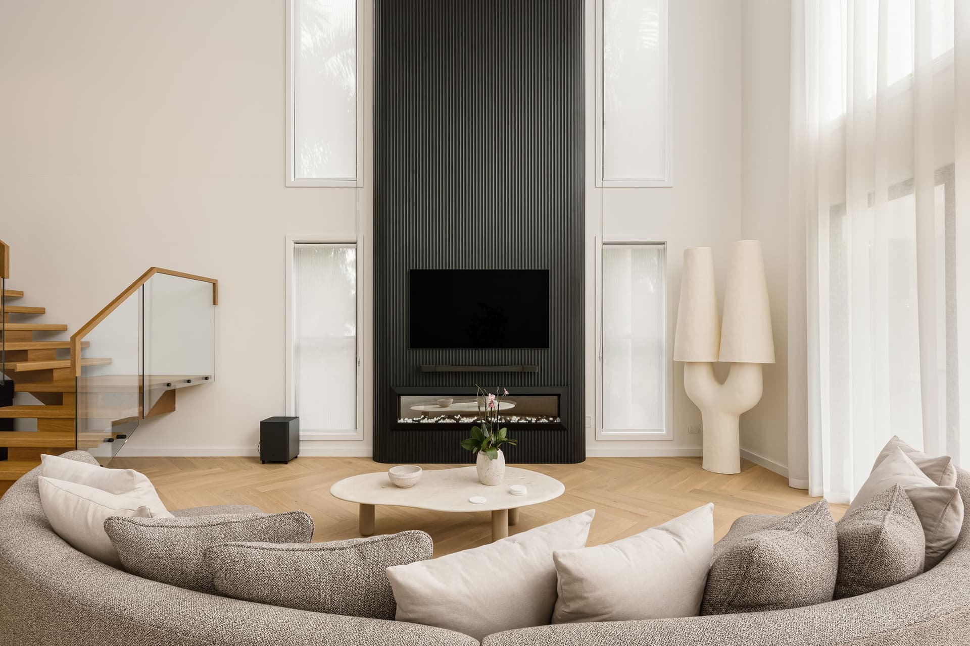 Living room with black fireplace wall and curved sofa