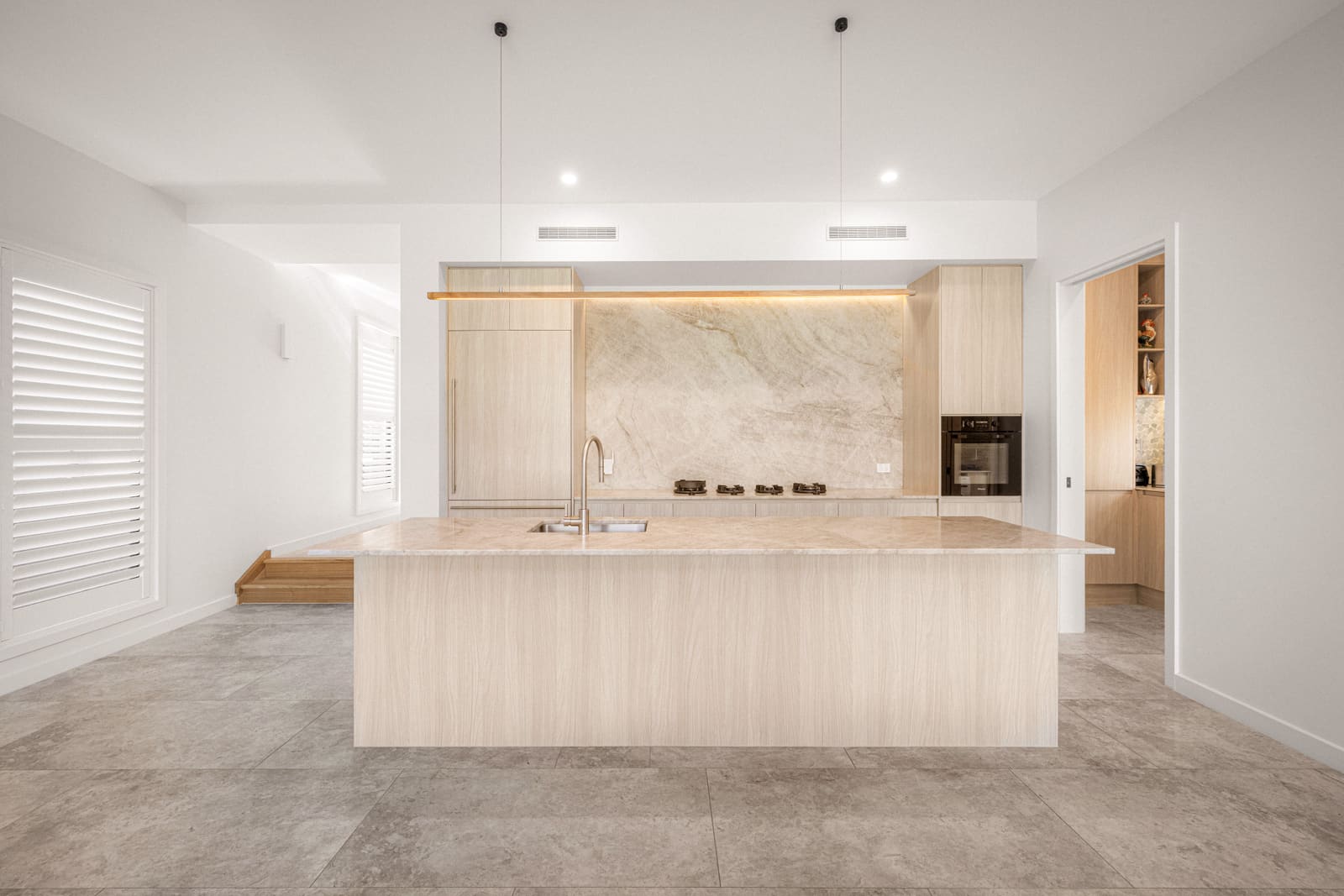 Kitchen with a natural stone splashback and timber island