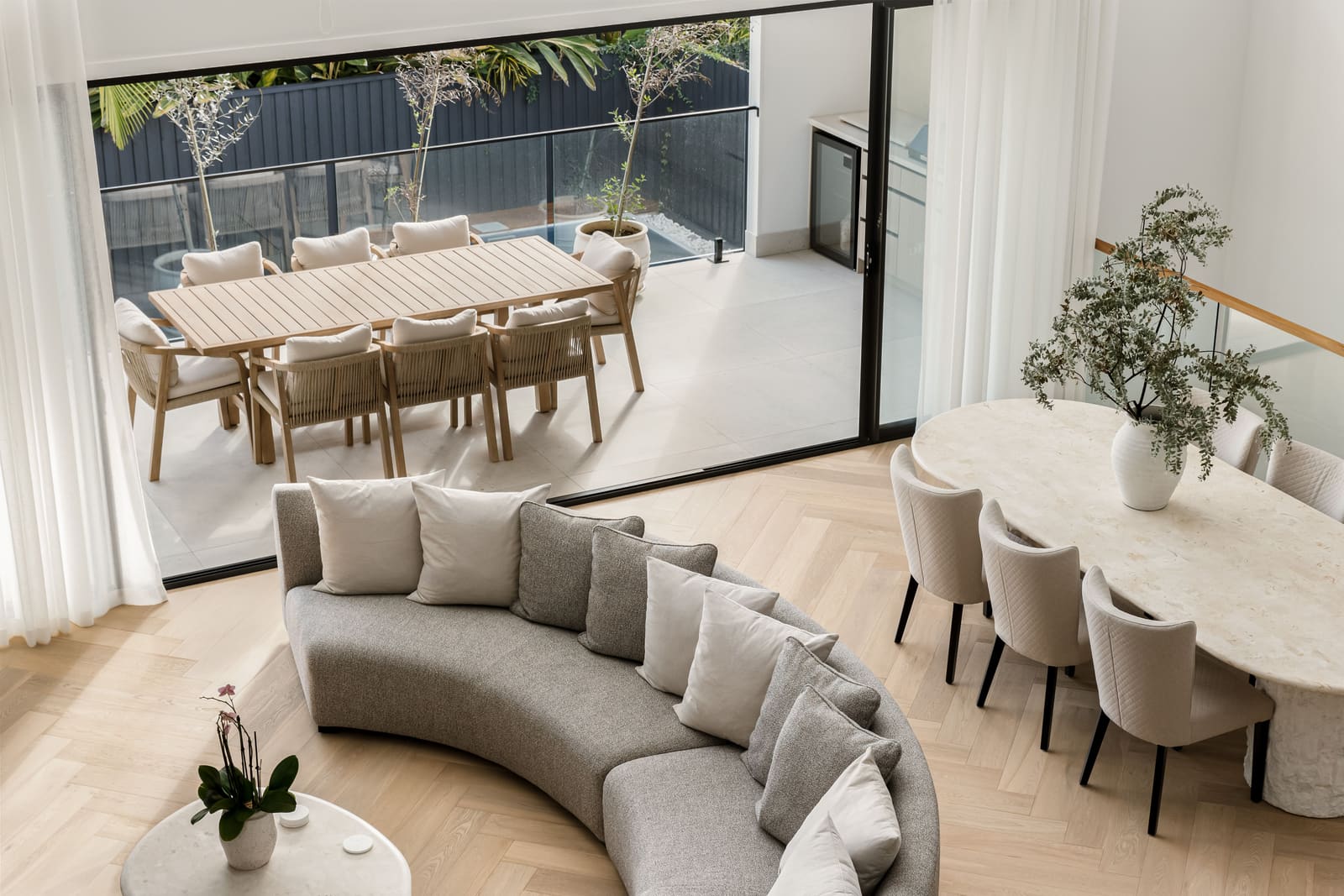 Curved sofa and dining table beneath a double-height ceiling