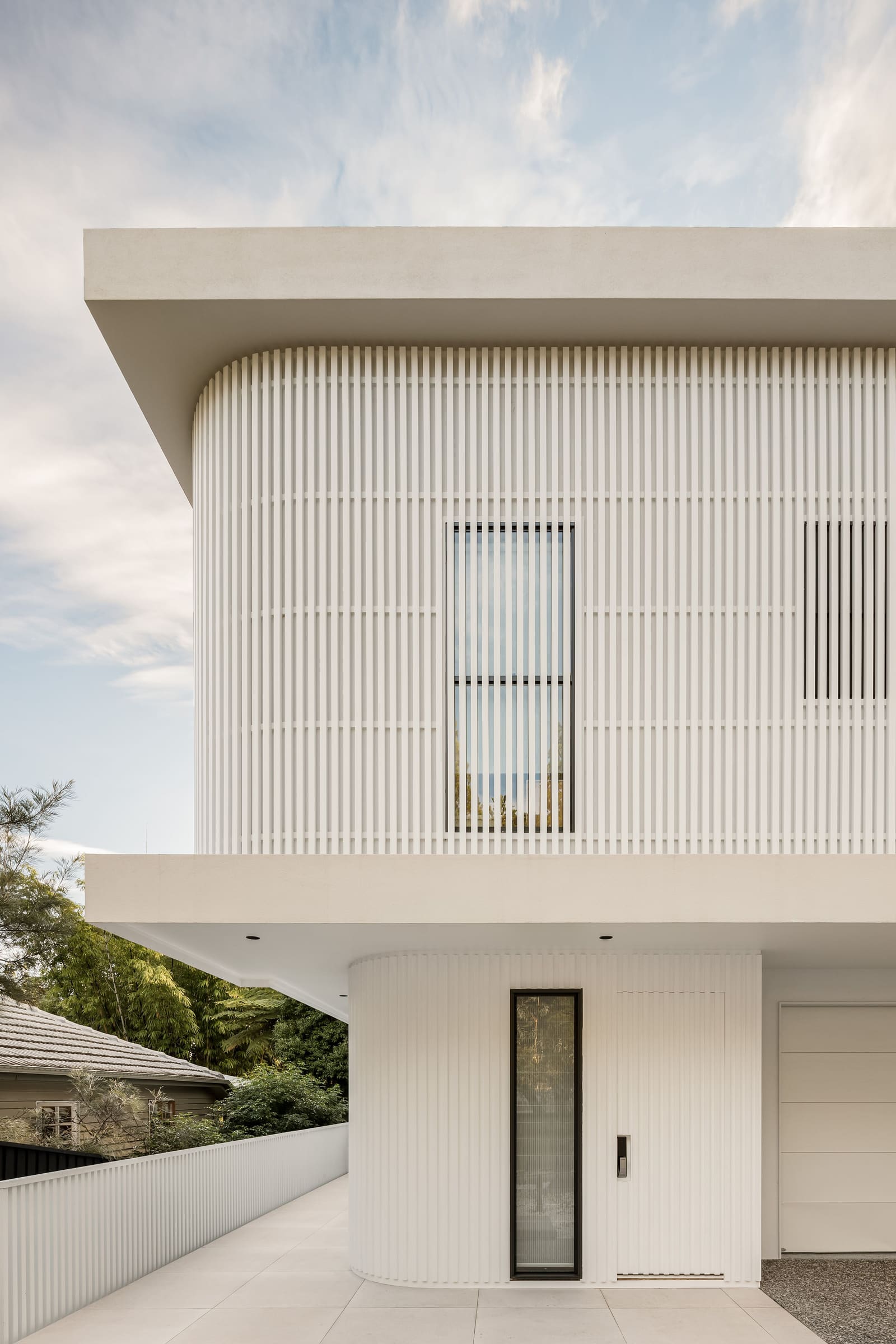Curved white facade wrapped in vertical battens