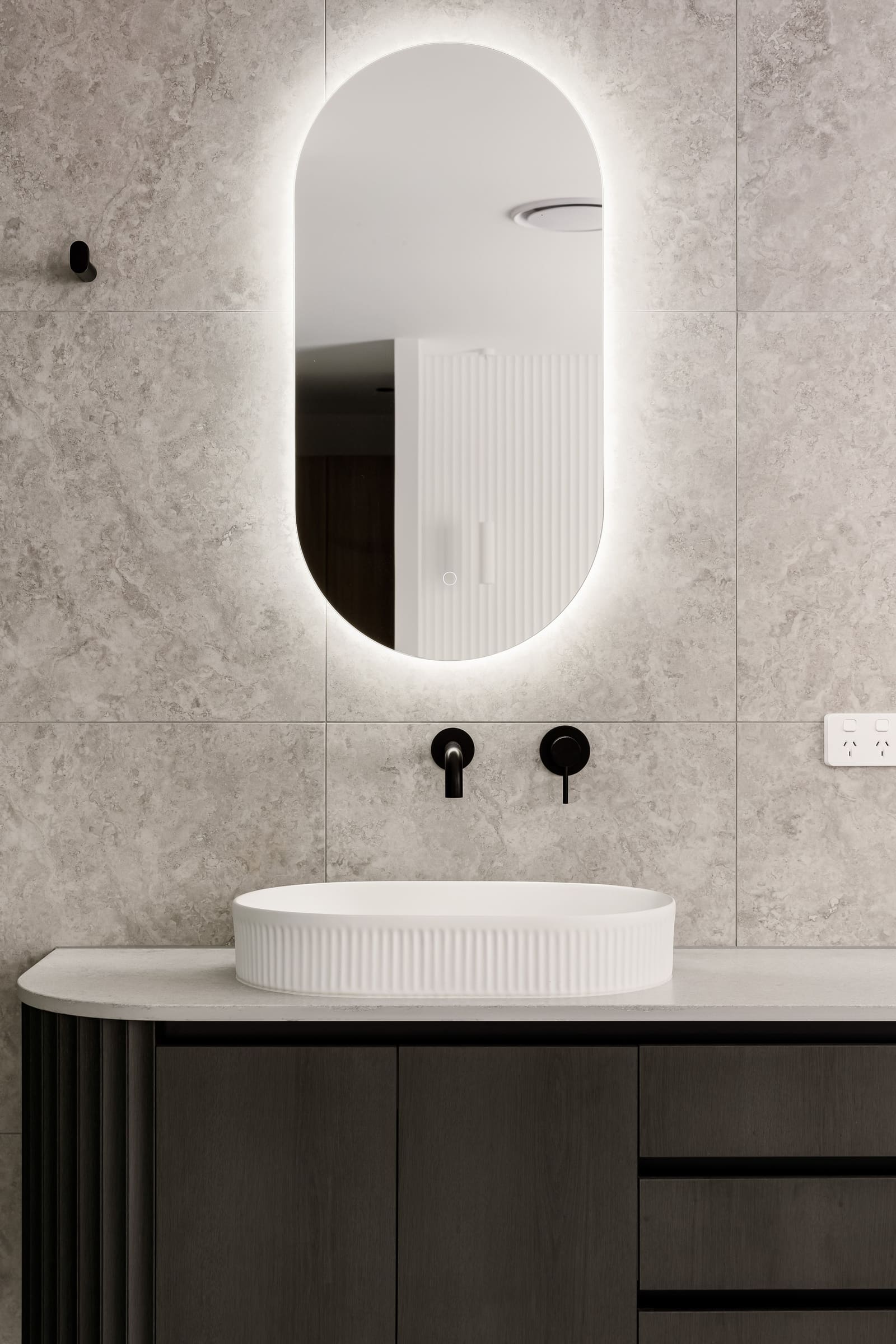 Ensuite vanity with a backlit oval mirror